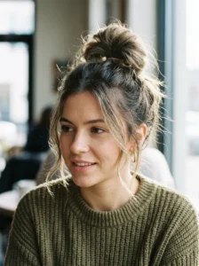 High messy bun with loose strands for greasy hair