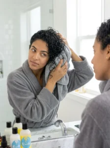 Gently drying curly hair with a microfiber towel to reduce frizz