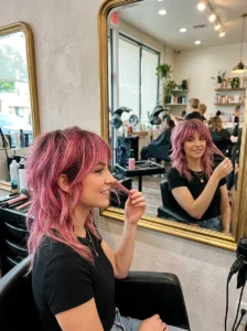 Woman examining the dimensional pink color in her finished wolf cut